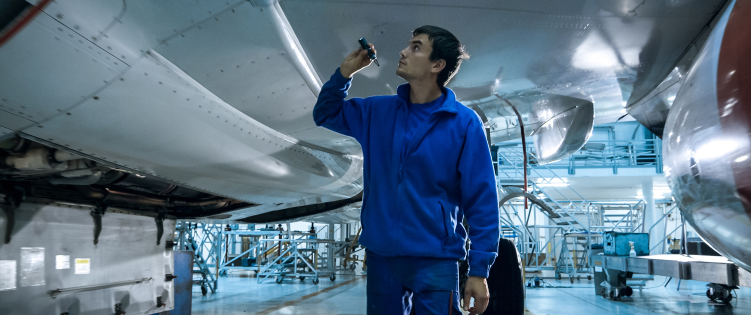 aircraft-maintenance-mechanic-with-flash-light-inspects-plane-fuselage-hangar